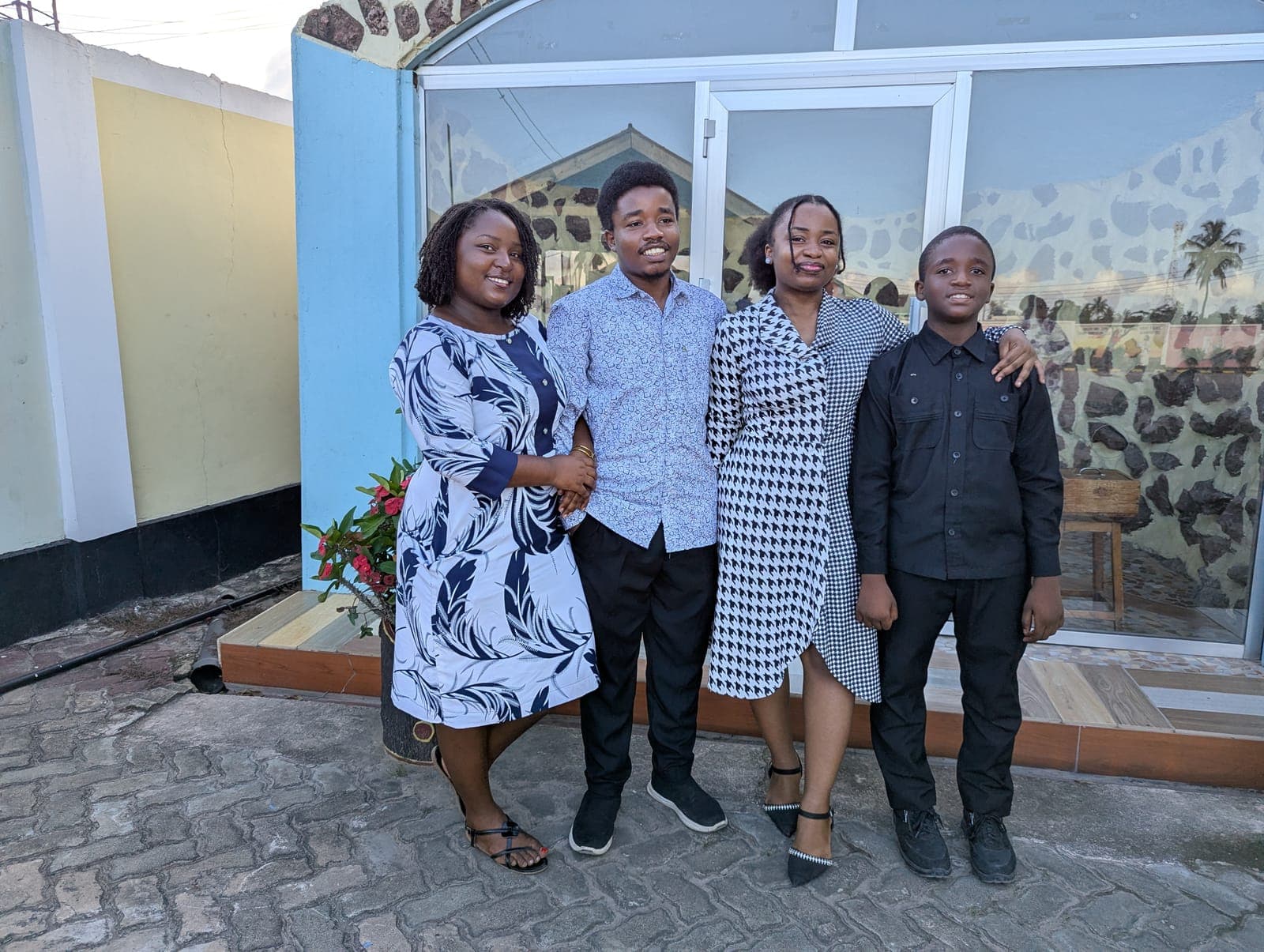Emmanuel with family, dressed up outside a home