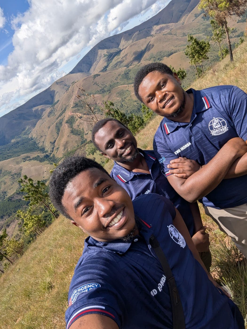 Emmanuel and friends on a grassy ridge, mountains behind