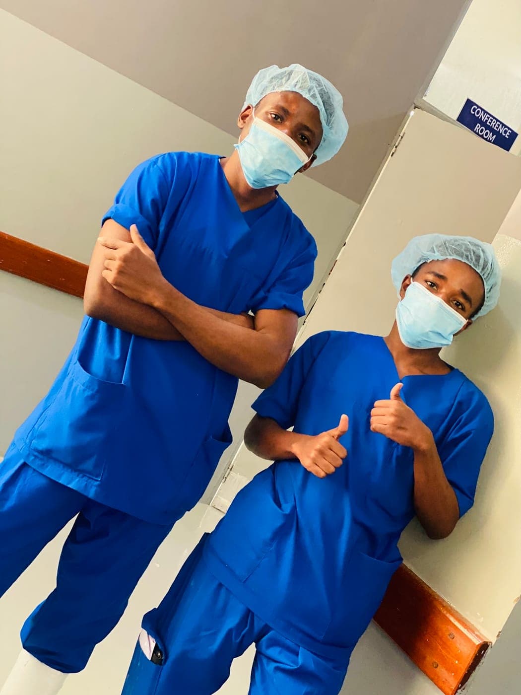 Emmanuel in surgical scrubs and cap with a colleague