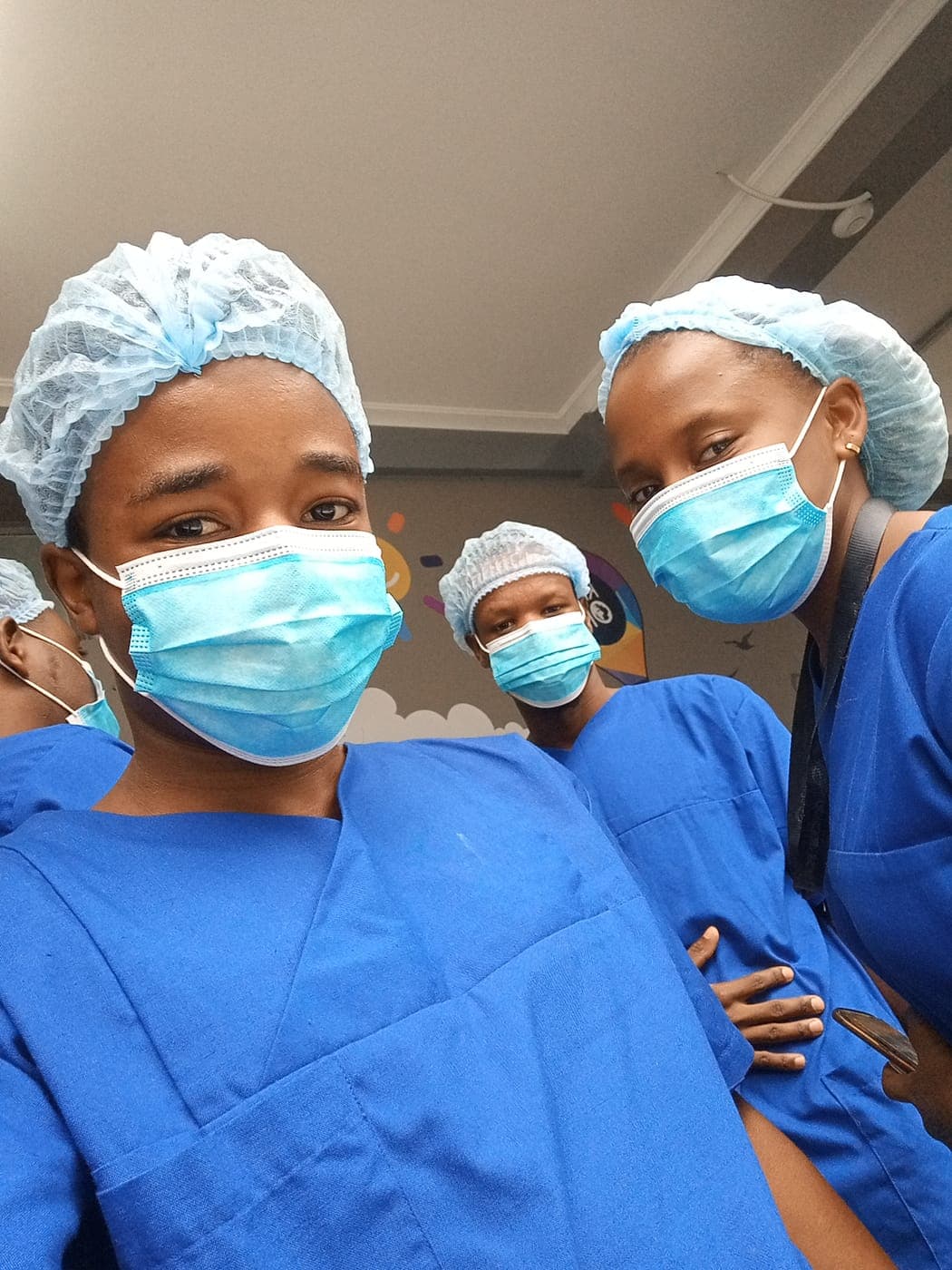 Emmanuel with colleagues in theatre scrubs and surgical caps