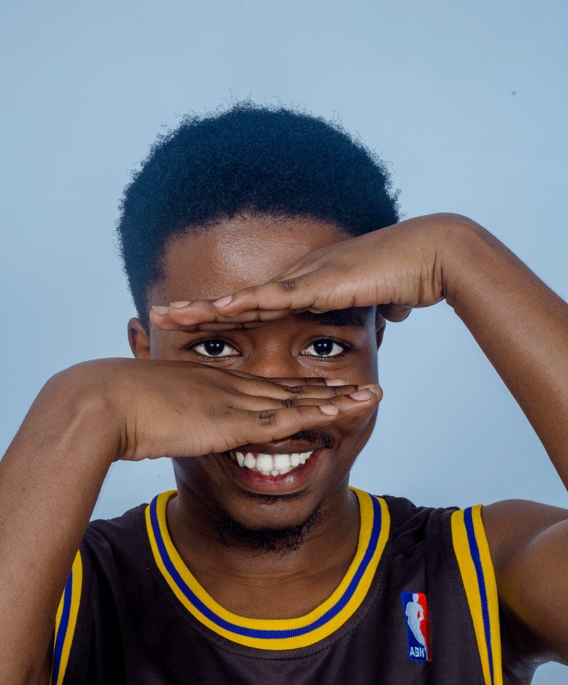 Emmanuel laughing, hands to his face, during a photo shoot